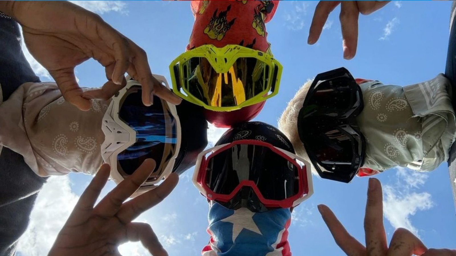 Quad Marrakech : quatre riders en lunettes de cross et bandanas, vus d’en dessous sur fond de ciel bleu