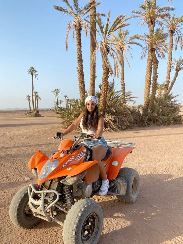 Pilote sur un quad orange sous les palmiers